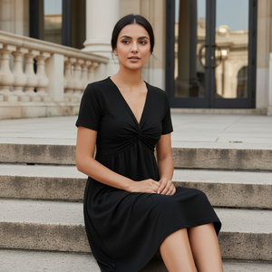 Woman in a black dress sitting on steps in front of a building