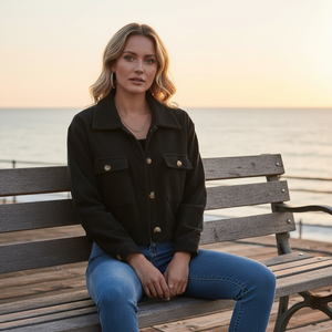 Woman sitting on a bench by the sea at sunset