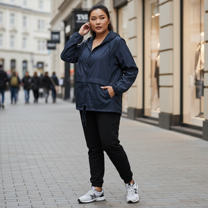 Woman in a navy blue jacket and black pants standing on a city street.