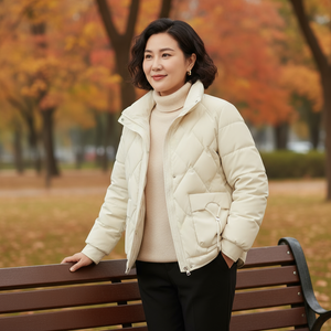 Woman in a beige puffer jacket standing on a bench with autumn trees in the background