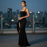 Woman in a black dress standing on a rooftop with city skyline in the background