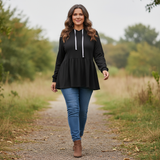 Woman wearing a black hoodie and blue jeans walking on a nature trail.