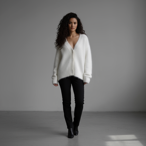 Woman wearing a white sweater and black pants against a gray background
