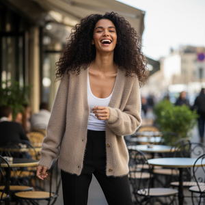Woman laughing outdoors in an urban setting with tables and chairs.