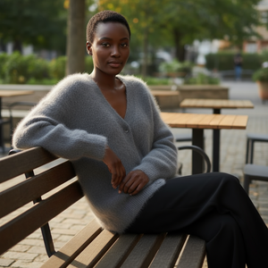 Woman sitting on a bench wearing a gray cardigan in an outdoor setting