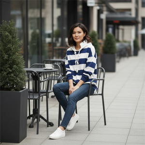 Woman sitting at an outdoor cafe table wearing a blue and white striped sweater.