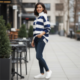 Woman wearing a blue and white striped sweater and jeans standing on a sidewalk.