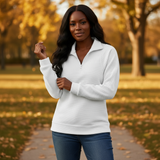 Woman wearing a white sweater and blue jeans standing in a park with autumn leaves.