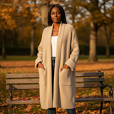 Woman wearing a long beige cardigan in an autumn park setting