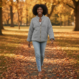 Woman walking in a park during autumn with fallen leaves on the ground.