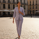 Woman in a light gray suit walking on a cobblestone street with blurred background
