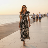 Woman in a zebra-striped dress standing on a promenade with people in the background.